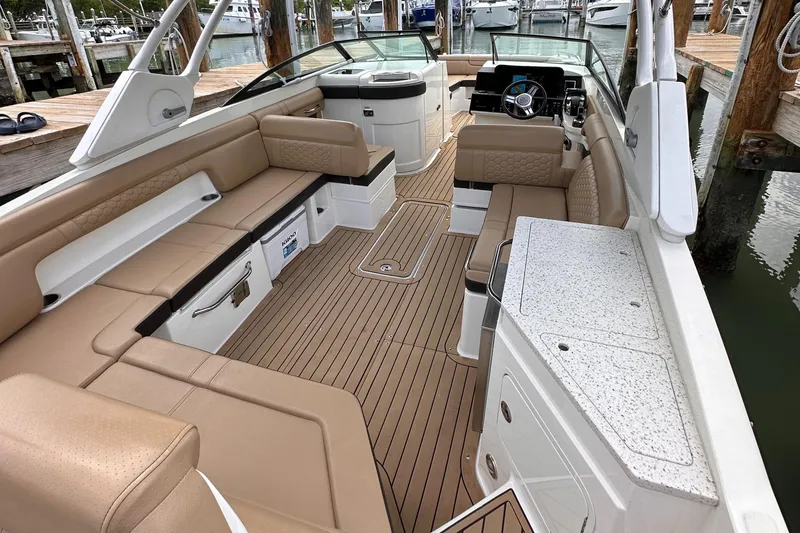 Slide: The Image of 2021 Sea Ray SDX 290 Outboard boat interior with tan seating and wood flooring. - 7
