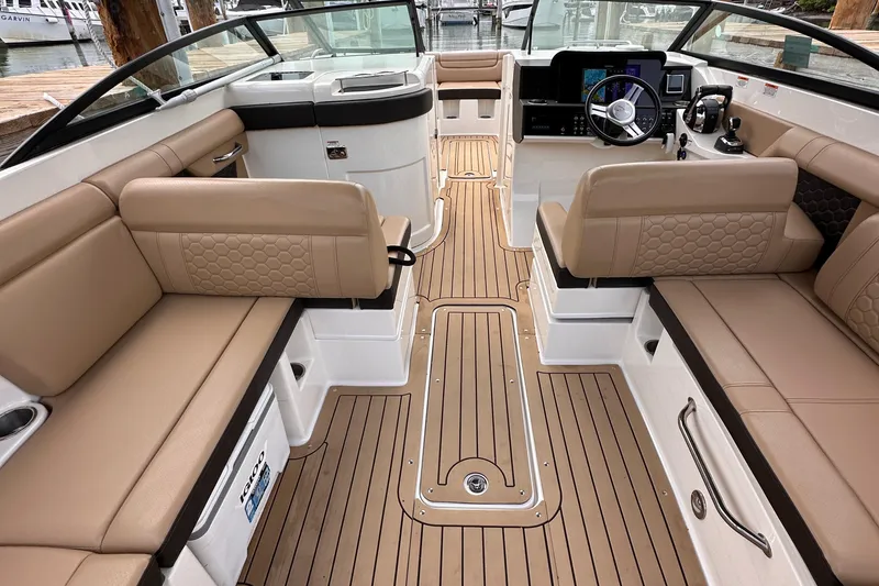 Slide: The Image of 2021 Sea Ray SDX 290 Outboard interior with tan seating and wood-style flooring. - 9