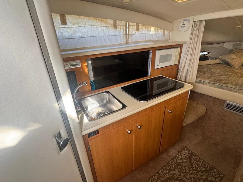 Slide: The Image of 2001 Bayliner 2855 LX Sunbridge interior with kitchenette, sink, stove, microwave, and cozy sleeping area. - 7