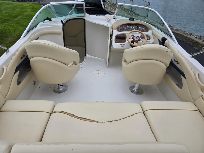 Slide: The Image of 2001 Sea Ray 210 Sundeck interior with beige seating and steering console. - 10