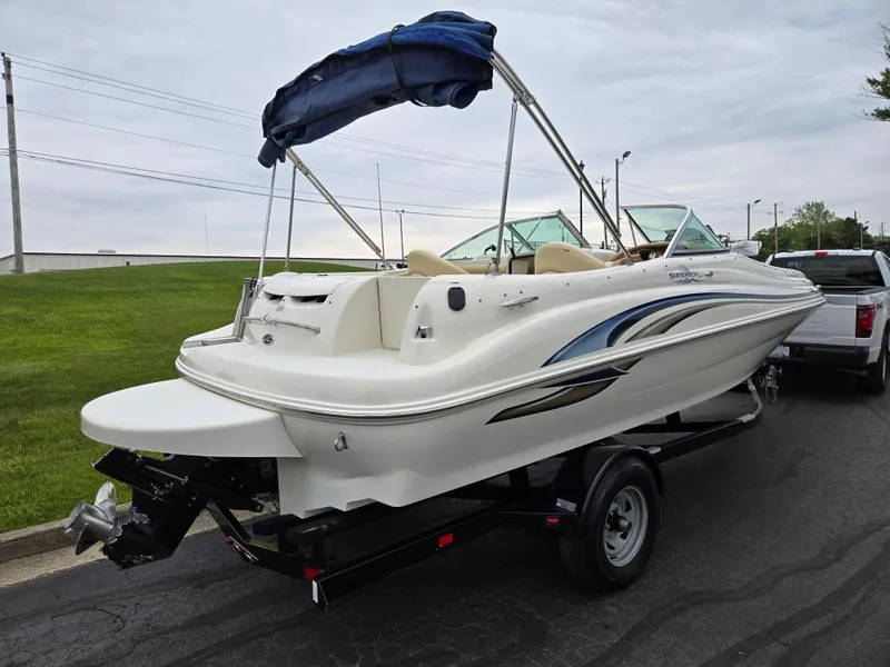 Slide: The Image of 2001 Sea Ray 210 Sundeck boat on trailer, white with blue accents, parked outdoors. - 3