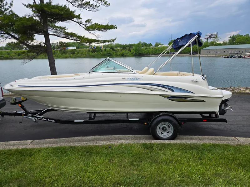 Slide: The Image of 2001 Sea Ray 210 Sundeck boat on trailer by a lake, under a cloudy sky. - 9