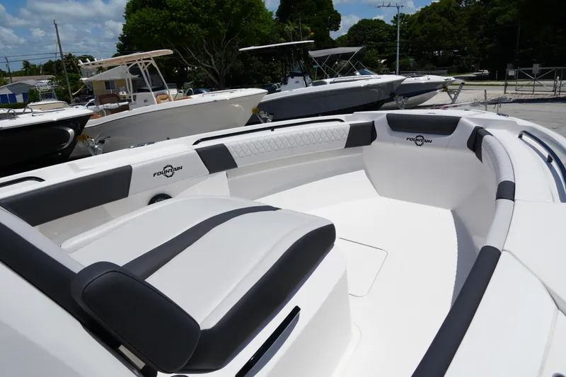 Slide: The Image of 2025 Fountain 32NX boat interior with cushioned seating, docked alongside other boats. - 11