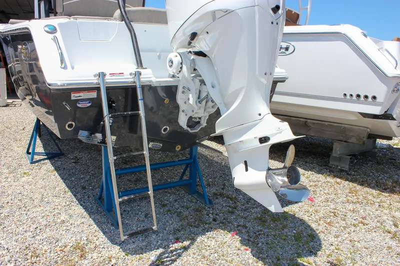 Slide: The Image of 2026 Sea Hunt Ultra 245 SE boat with outboard motor and ladder on gravel. - 13