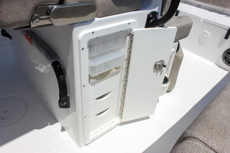 Slide: The Image of 2026 Sea Hunt Ultra 245 SE boat storage compartment with open door and organized shelves. - 26