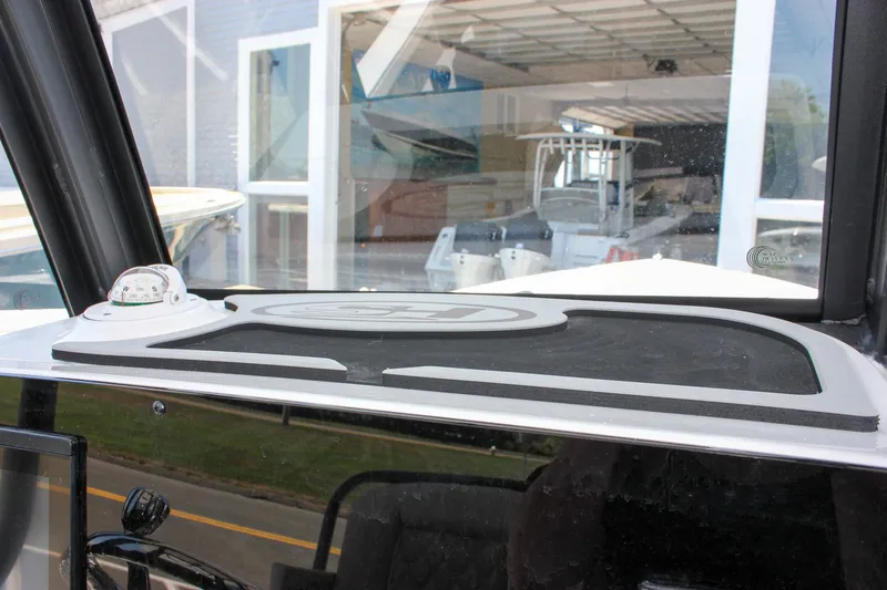 Slide: The Image of 2026 Sea Hunt Ultra 245 SE dashboard with compass, viewed in a showroom setting. - 31