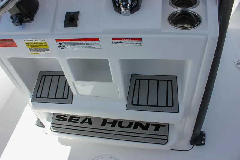 Slide: The Image of 2026 Sea Hunt Ultra 245 SE boat console with cup holders and warning labels. - 33