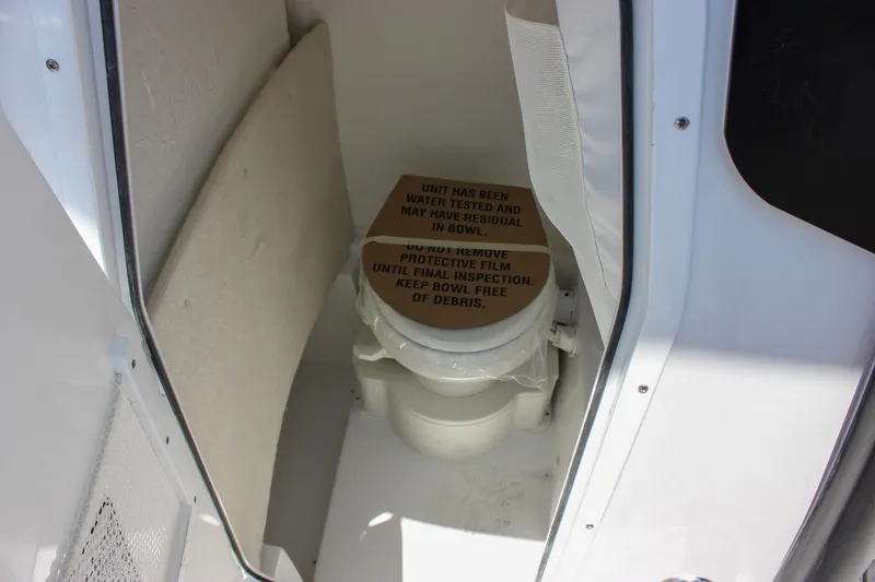 Slide: The Image of 2026 Sea Hunt Ultra 245 SE boat toilet with protective film and inspection notice. - 43