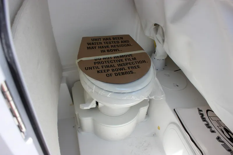 Slide: The Image of 2026 Sea Hunt Ultra 245 SE boat toilet with protective film and inspection notice. - 44
