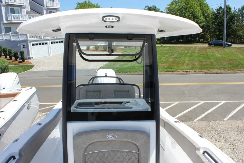 Slide: The Image of 2026 Sea Hunt Ultra 245 SE boat console with seating, parked near residential area. - 7