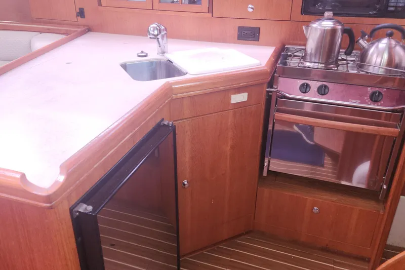 Slide: The Image of Compact kitchen in a 2004 Hunter 36 yacht with stove, sink, and wooden cabinetry. - 23