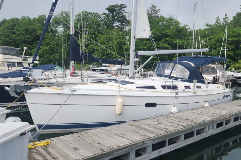 Slide: The Image of 2004 Hunter 36 sailboat docked at marina, surrounded by lush greenery. - 40