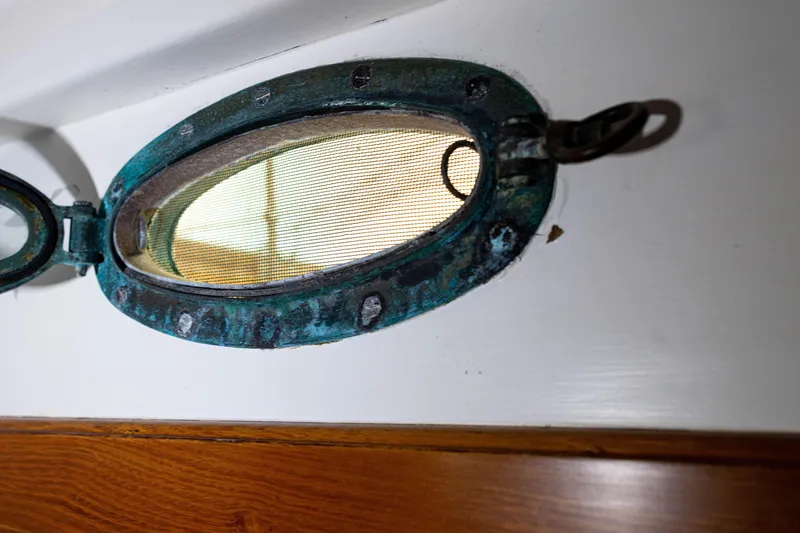 Slide: The Image of Vintage Concordia 39 porthole, 1964, with weathered patina and wooden interior detail. - 14