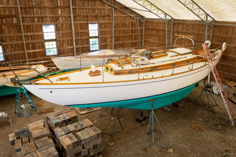 Slide: The Image of 1964 Concordia 39 sailboat in a wooden shed, elevated on stands for maintenance. - 2