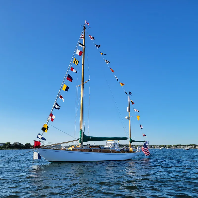 Slide: The Image of Classic 1964 Concordia 39 sailboat adorned with colorful flags on a sunny day. - 4