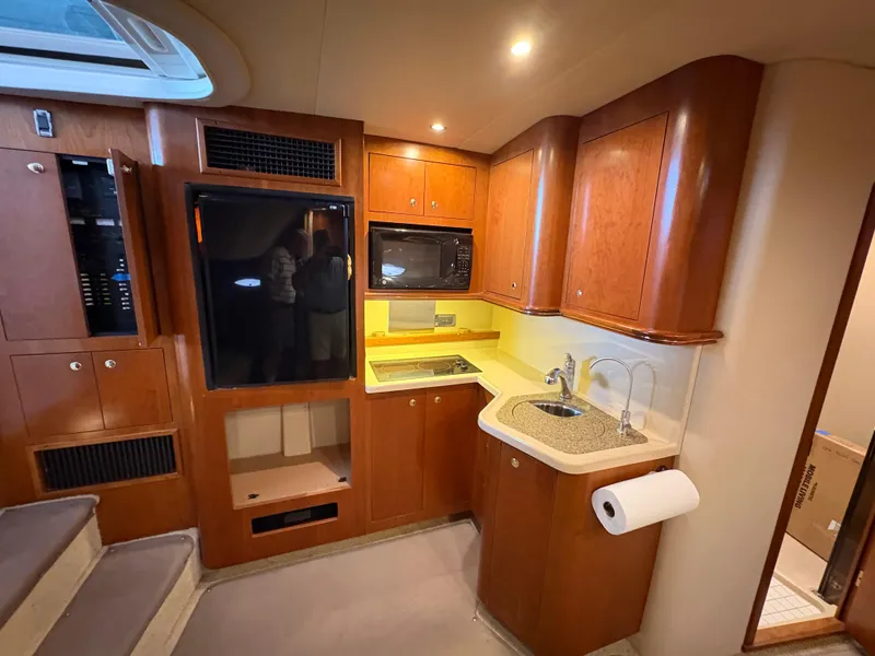 Slide: The Image of 2001 Cruisers 3672 Express yacht interior with kitchenette, featuring wood cabinets and modern appliances. - 7