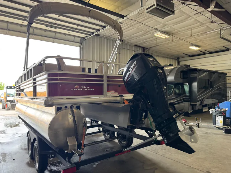 Slide: The Image of 2021 Sun Tracker Fishin' Barge 20 DLX pontoon boat in a garage with Mercury outboard motor. - 4