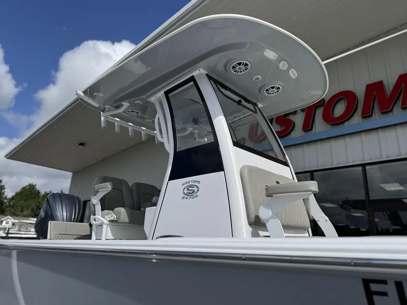 Slide: The Image of 2024 Sportsman Masters 247OE Bay Boat with T-top and seating, displayed outdoors. - 6