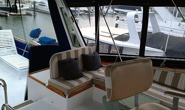 Slide: The Image of 1986 Sea Ranger 47 Pilothouse interior with striped seating and marina view. - 5