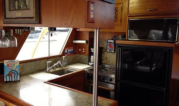 Slide: The Image of 1986 Sea Ranger 47 Pilothouse kitchen with granite countertops, stove, and microwave. - 7