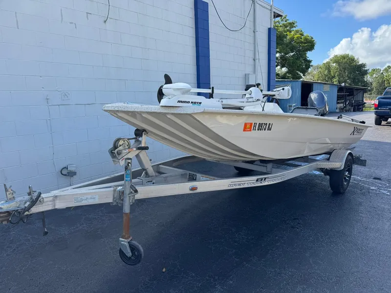 Slide: The Image of 2016 Xpress HD16DB boat on trailer, parked outdoors near a building. - 2