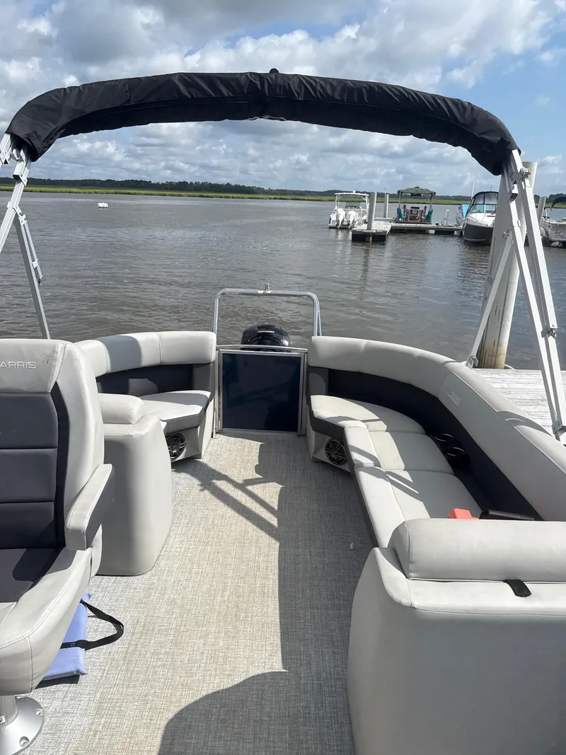 Slide: The Image of 2024 Harris Cruiser 230 pontoon boat with spacious seating, docked on a sunny day. - 4