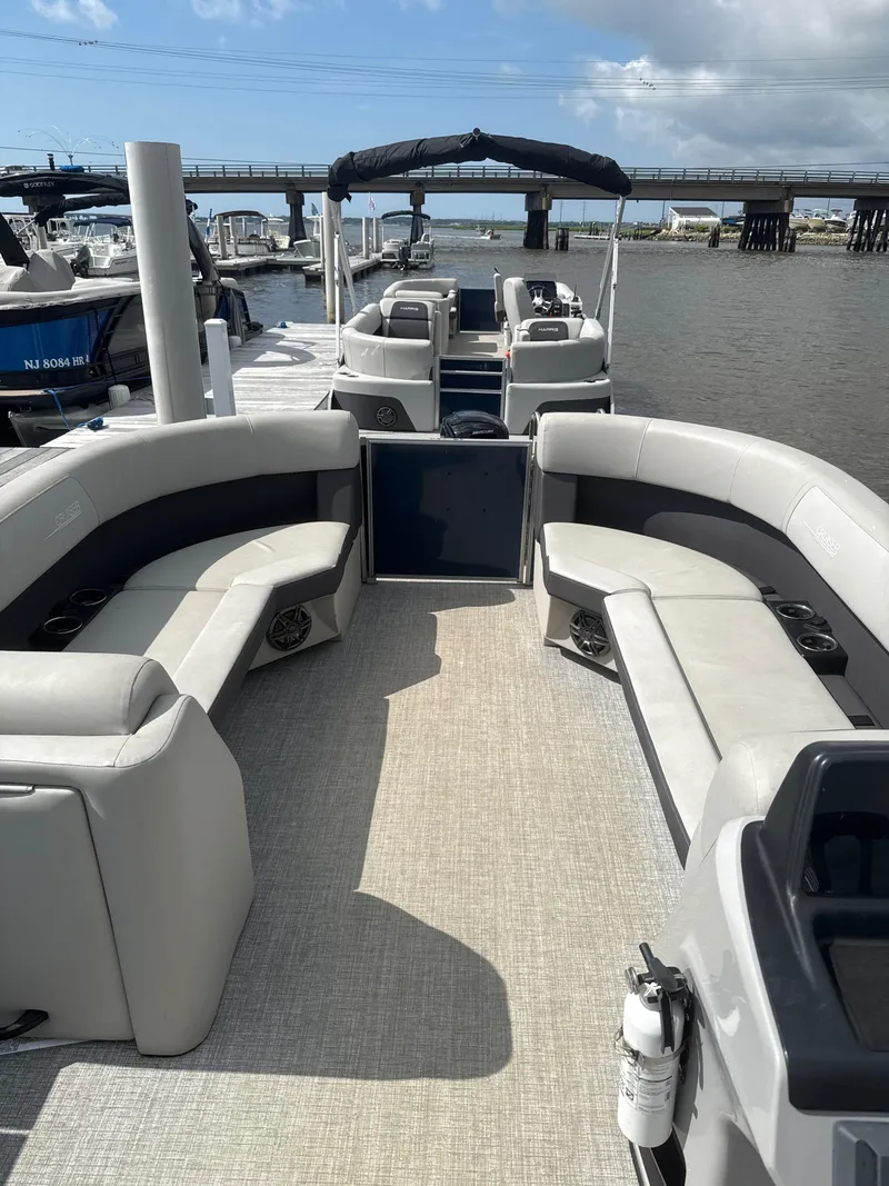Slide: The Image of 2024 Harris Cruiser 230 pontoon boat with spacious seating, docked by a bridge. - 9