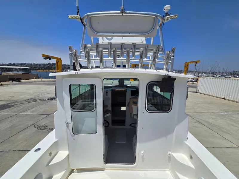 Slide: The Image of 2019 Parker 2520 DV boat docked, rear view showing cabin entrance and fishing rod holders. - 17