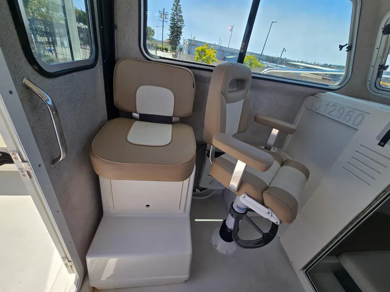 Slide: The Image of Interior seating of a 2019 Parker 2520 DV boat, featuring beige and white cushioned chairs. - 20