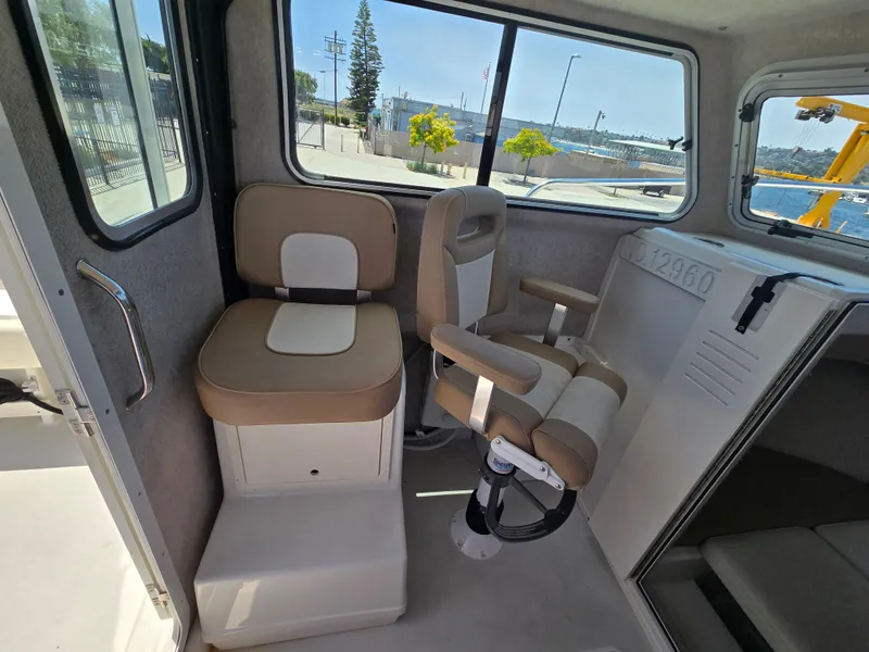Slide: The Image of Interior of a 2019 Parker 2520 DV boat with beige seating and windows. - 21