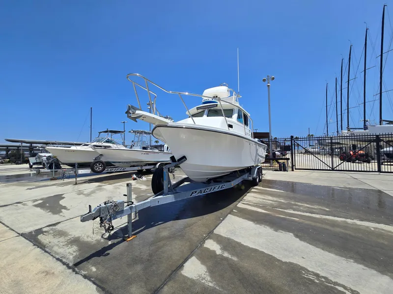 Slide: The Image of 2019 Parker 2520 DV boat on trailer at marina under clear blue sky. - 45