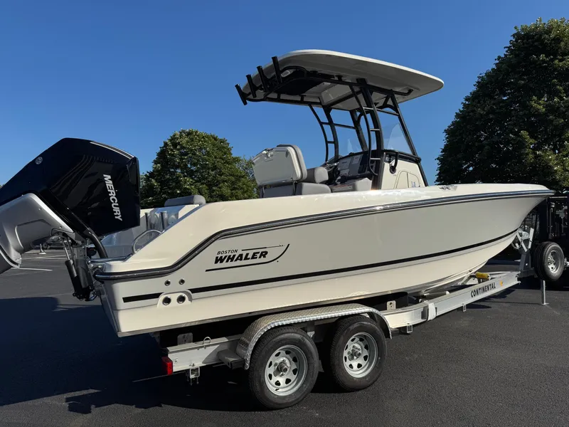 Slide: The Image of 2025 Boston Whaler 230 Outrage boat on trailer, featuring Mercury engine, parked outdoors. - 4