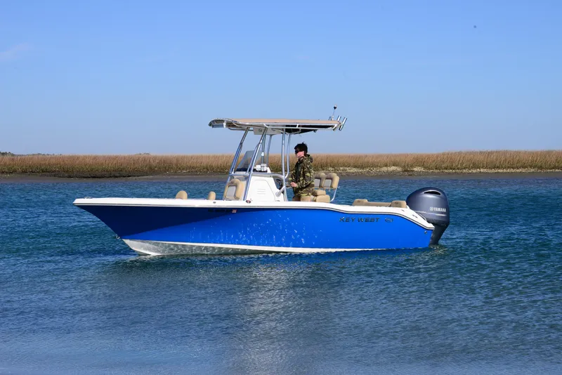 Slide: The Image of 2020 Key West 219 FS boat cruising on calm water, blue hull, clear sky. - 4