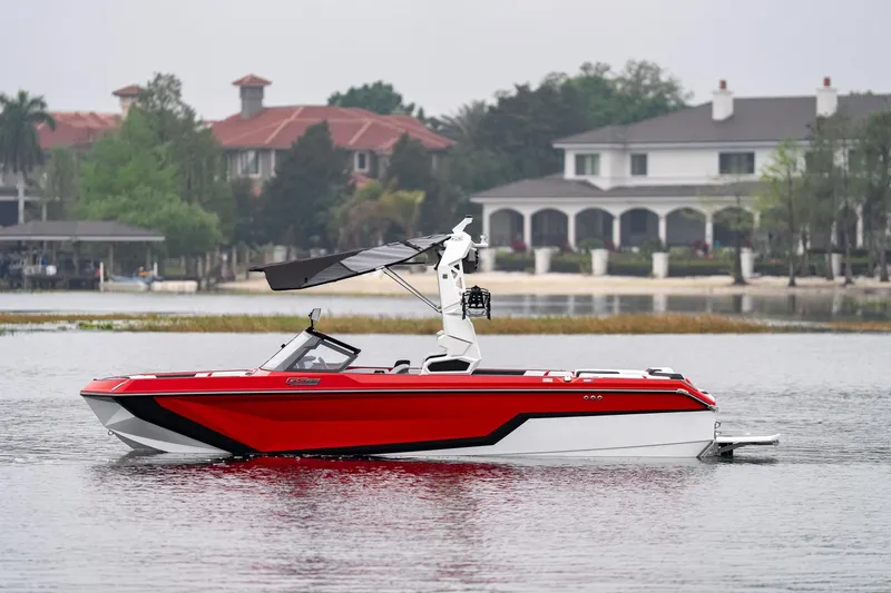 Slide: The Image of 2026 Nautique Super Air Nautique GS22 boat on a lake, with luxury homes in the background. - 0