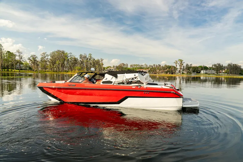 Slide: The Image of 2026 Nautique Super Air Nautique GS22 boat on calm lake, surrounded by trees. - 12