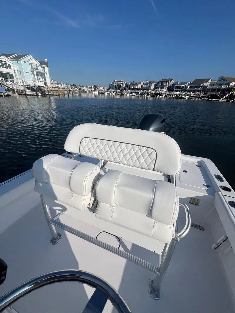 Slide: The Image of 2023 Sportsman Masters 207 Bay Boat with white seating, docked in a scenic marina. - 12