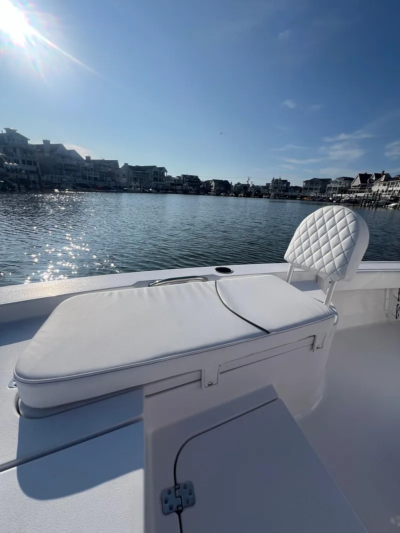 Slide: The Image of 2023 Sportsman Masters 207 Bay Boat on calm water, featuring cushioned seating and sunny weather. - 7