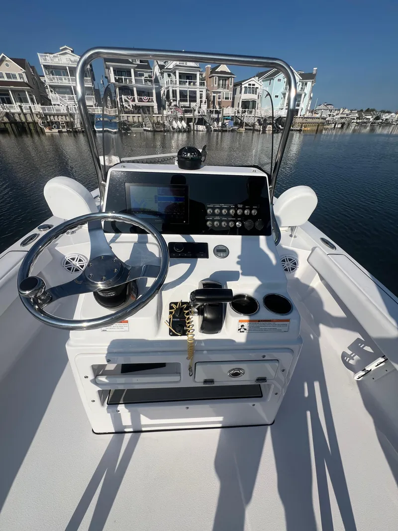 Slide: The Image of 2023 Sportsman Masters 207 Bay Boat console with steering wheel, controls, and waterfront view. - 9