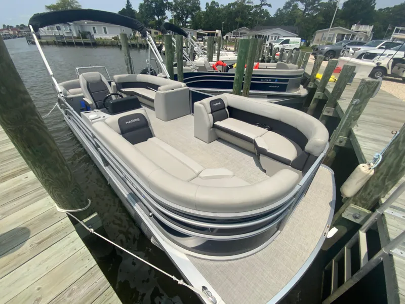 Slide: The Image of 2024 Harris Cruiser 230 pontoon boat docked, featuring spacious seating and modern design. - 3