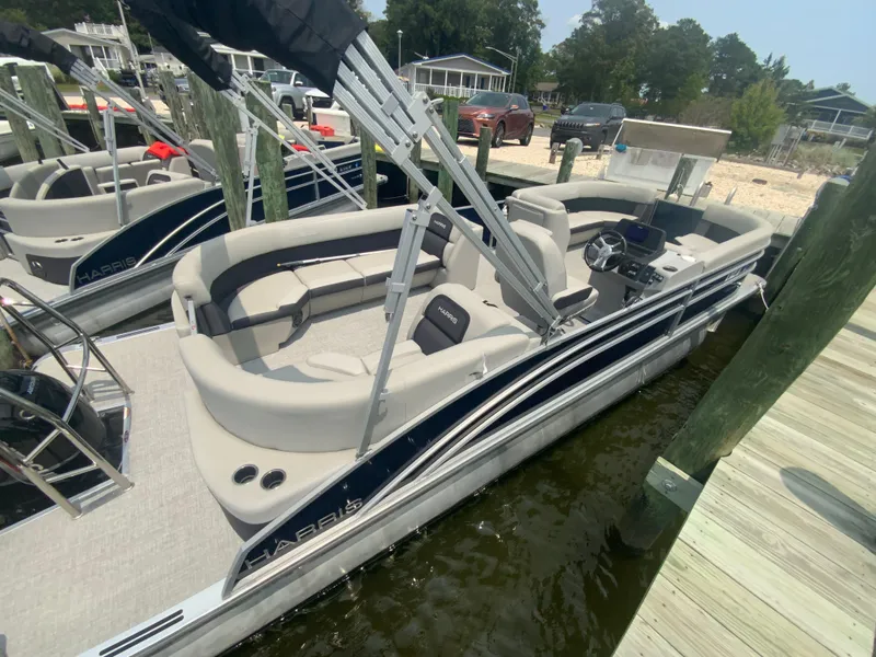Slide: The Image of 2024 Harris Cruiser 230 pontoon boat docked, featuring spacious seating and sleek design. - 4