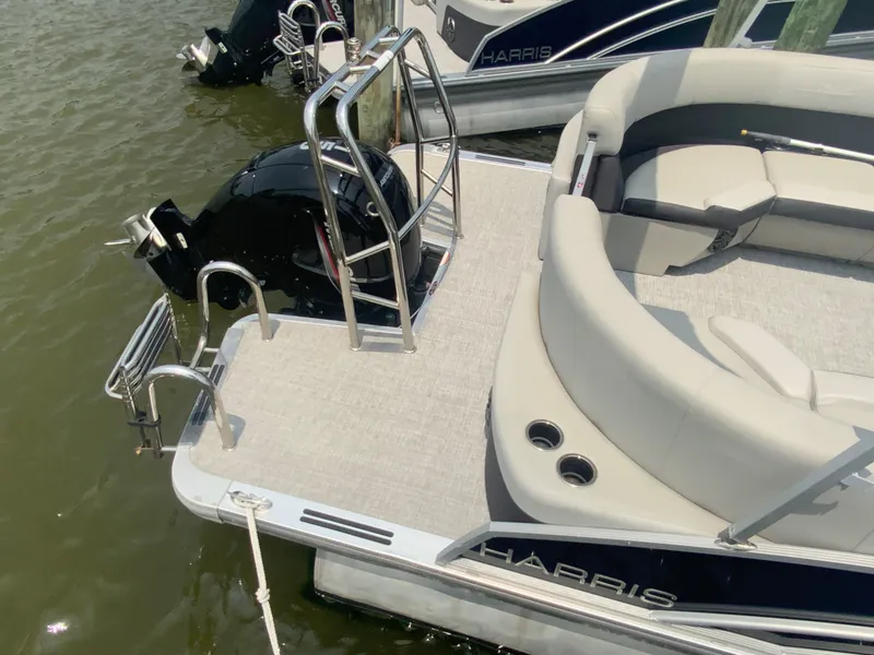 Slide: The Image of 2024 Harris Cruiser 230 boat with seating and motor, docked on water. - 5