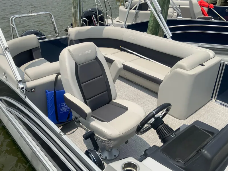 Slide: The Image of 2024 Harris Cruiser 230 pontoon boat interior with plush seating and steering console. - 7