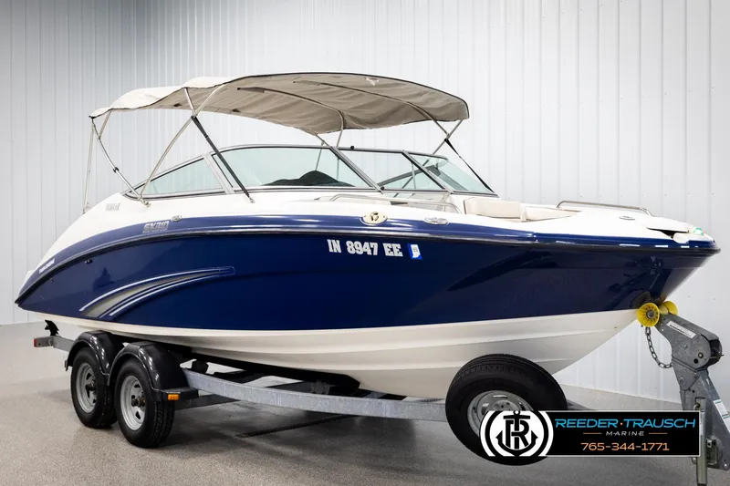Slide: The Image of 2013 Yamaha Boats 210 SX on trailer, blue and white, with canopy, displayed indoors. - 3