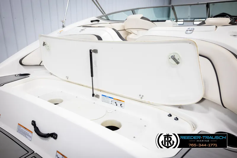 Slide: The Image of 2013 Yamaha Boats 210 SX interior with open storage compartment, white seating, and marine branding. - 44