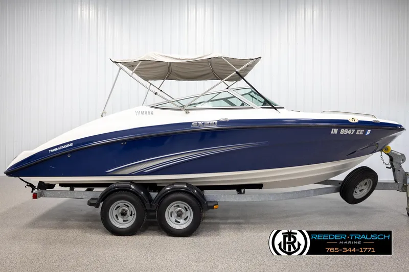 Slide: The Image of 2013 Yamaha Boats 210 SX, blue and white, on trailer, with canopy, in showroom. - 5