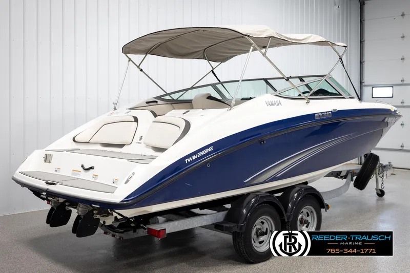 Slide: The Image of 2013 Yamaha Boats 210 SX, blue and white, twin-engine, on trailer in showroom. - 6