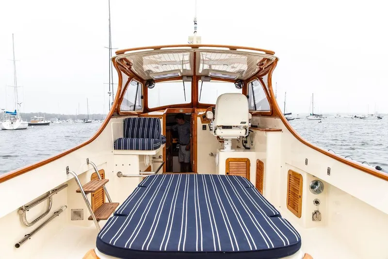 Slide: The Image of 1999 Hinckley Picnic Boat Classic with striped seating, docked in a marina. - 10