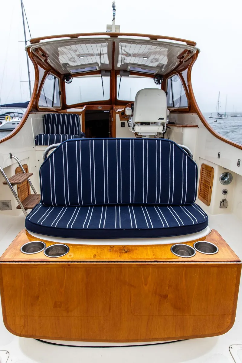 Slide: The Image of 1999 Hinckley Picnic Boat Classic with striped seating and wooden accents, docked at a marina. - 11