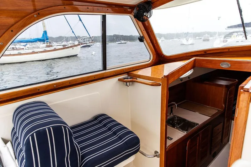 Slide: The Image of Interior of a 1999 Hinckley Picnic Boat Classic with striped seating and wooden cabinetry. - 12