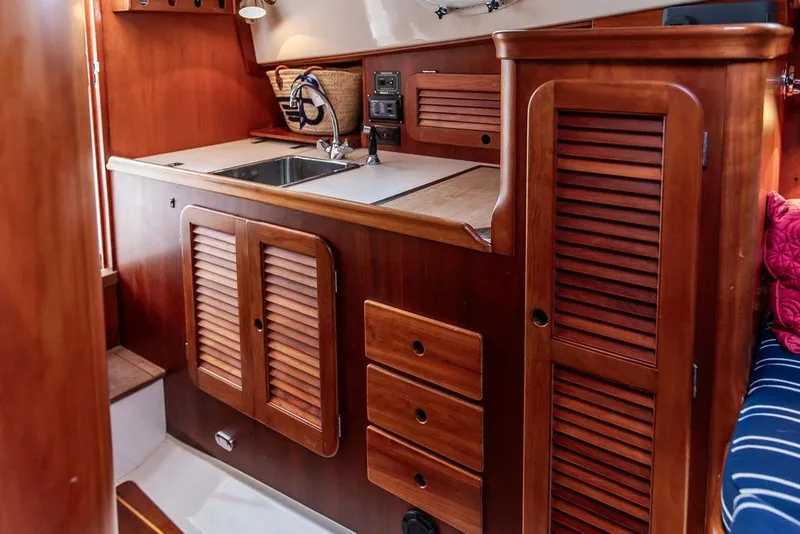 Slide: The Image of 1999 Hinckley Picnic Boat Classic interior with wooden cabinetry and compact kitchen area. - 17